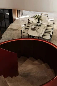 Modern dining room featuring a marble table and chairs, accompanied by a spiral staircase.