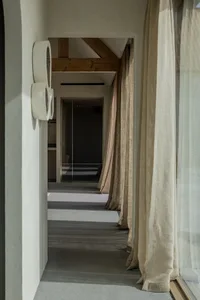 A modern interior corridor with textured wall curtains hanging in front of glass windows.