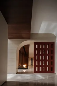 A modern lobby with marble flooring and walls, featuring an artistic red grid partition and a spherical light fixture.