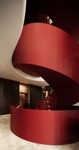 A modern, red, metallic staircase with a sleek, curved design.