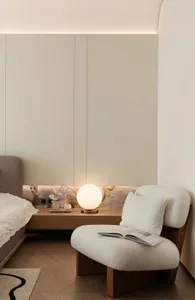 Minimalist bedroom with soft, neutral-toned furnishings and a round, spherical lamp on a modern nightstand.