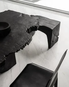 A modern, industrial-style black wooden table with a natural, raw finish.
