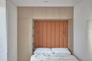 A minimalist bedroom with neutral-toned furniture and layered bedding.