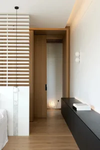 A modern minimalist bedroom featuring wooden elements and a sleek black sideboard.