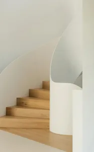 A minimalist interior space featuring white wooden steps and a white wall.