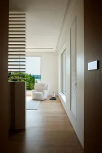 A minimalist living room with wood flooring and glass features, showcasing a comfortable seating area.