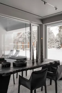 Modern minimalist living room featuring a black wooden table and black chairs.