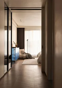 A modern bedroom featuring wooden paneling, a white floor lamp, and a blue dresser.
