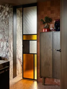 A modern bathroom interior with a glass door featuring geometric patterns.