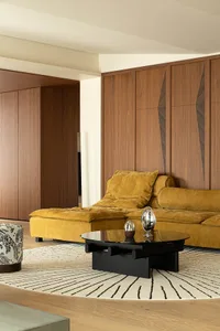 A modern living room with wooden furniture and a mustard-colored sofa.