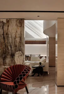 Modern living room with white marble walls, red curved furniture, and white couches in a contemporary space.