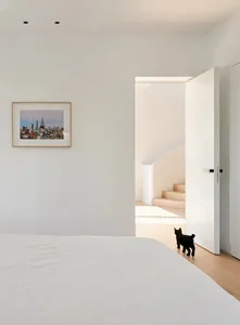 A minimalist bedroom with a wood floor and white walls.