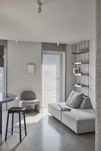 Modern living room with neutral-colored furniture and concrete flooring and walls.