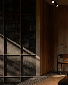 A minimalist bedroom featuring wooden paneling and a light wooden chair.