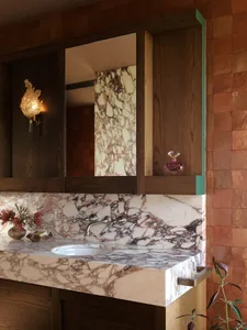 A modern bathroom featuring a marble countertop with a white sink and a wooden vanity.