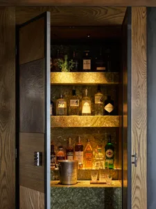 A well-stocked bar cabinet with various bottles of alcohol and a champagne bucket.