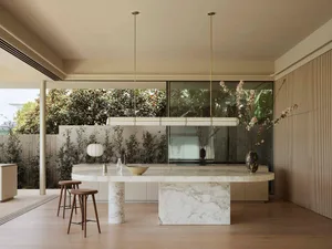 Modern kitchen interior featuring a marble countertop and island, with a minimalist aesthetic and large windows.