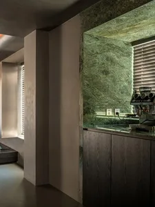 Modern kitchen interior featuring a granite countertop with a dark wood cabinet and a coffee machine.
