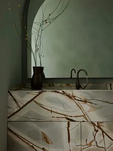 Modern bathroom with a marble countertop featuring dark veins, a black faucet, and a vase with dried branches on a circular w