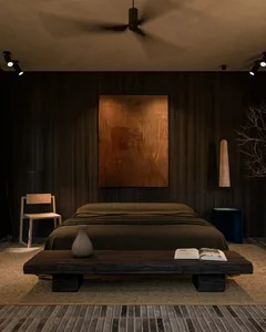 A minimalist bedroom with dark walls, wooden floors, and a low wooden bed platform.