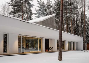 Modern minimalist house with concrete and glass materials and a snowy exterior