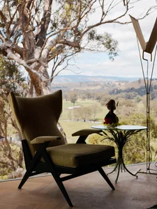 Modern minimalist living room featuring a wood and velvet upholstered chair with a scenic landscape view.