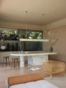 A modern minimalist kitchen with marble countertops and seating area.