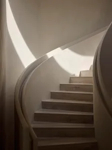 A minimalist staircase made of wood, featuring smooth, curved lines.