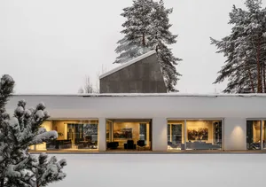 A modern residential house with a minimalist design, featuring a concrete shell and large glass windows.