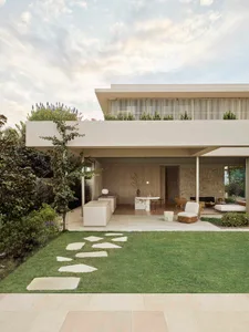 Modern residential home exterior with sandstone facade and rooftop garden.