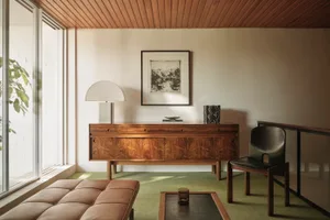 A mid-century modern living room featuring wooden furniture and a green carpet.