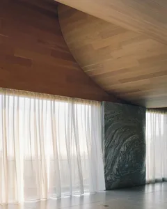 Minimalist interior space featuring wood-paneled walls and ceiling, with transparent fabric curtains.