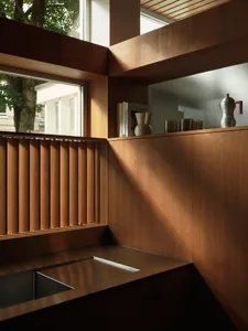 A minimalist kitchen featuring wooden shelves and a stainless steel sink.