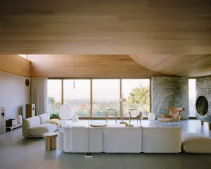 Modern minimalist living room featuring open floor plan and large windows overlooking a scenic outdoor view with wooden furni