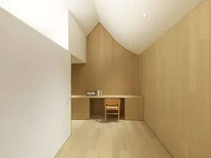Minimalist workspace with wooden flooring, walls, and desk.