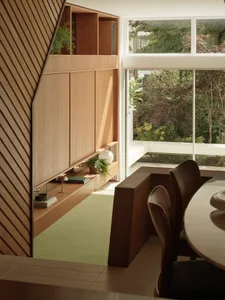 A modern kitchen with wooden shelves, green plants, and a glass window overlooking a garden.