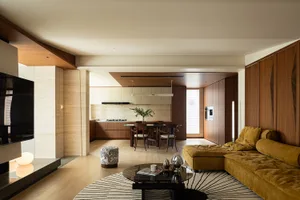 A modern living room featuring wooden flooring, a yellow sectional sofa, and a coffee table.