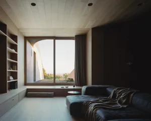 Modern minimalist living room with wooden flooring, furniture, and built-in shelves.