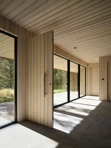 Modern interior design with wooden walls and floor, large glass windows, and concrete flooring.