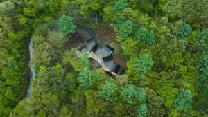 Aerial view of a nature center with timber construction surrounded by lush green trees.
