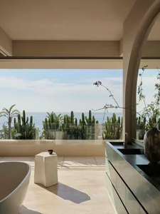 Modern minimalist bathroom featuring marble countertops, concrete walls, and ceramic tiling with a view of the ocean.