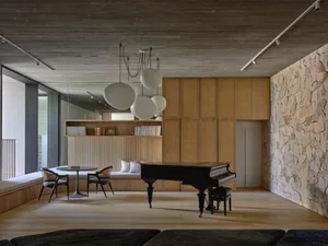 Modern minimalist living room featuring wooden furniture, concrete walls, and stone accents.