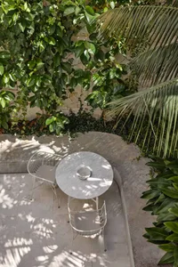 A minimalist outdoor seating area featuring a round concrete table and two matching chairs.