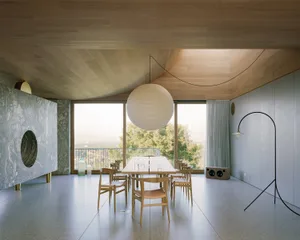 Modern dining room with sleek wooden furniture, concrete flooring, and a large spherical light fixture hanging from the curve