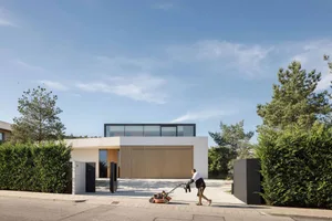 A modern house featuring concrete and glass materials with a clear front view of the exterior.
