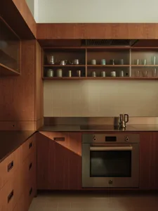 Modern kitchen with wooden cabinets and glass countertops, featuring a built-in stove and oven.
