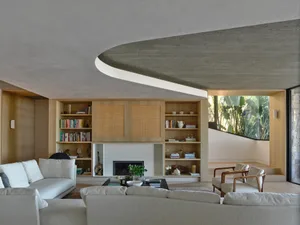 Modern living room featuring a concrete ceiling, wooden furniture, and glass windows with a view of greenery.
