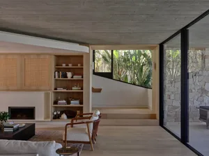 Modern, minimalist living room featuring wood furniture, concrete walls, and stone accents.