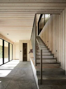 A minimalist living room with wooden walls and concrete flooring, featuring modern furniture and natural light.