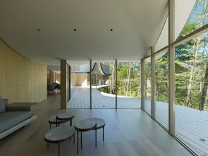 Modern living room with open-plan design, featuring wooden flooring and glass walls, providing a spacious and inviting atmosp